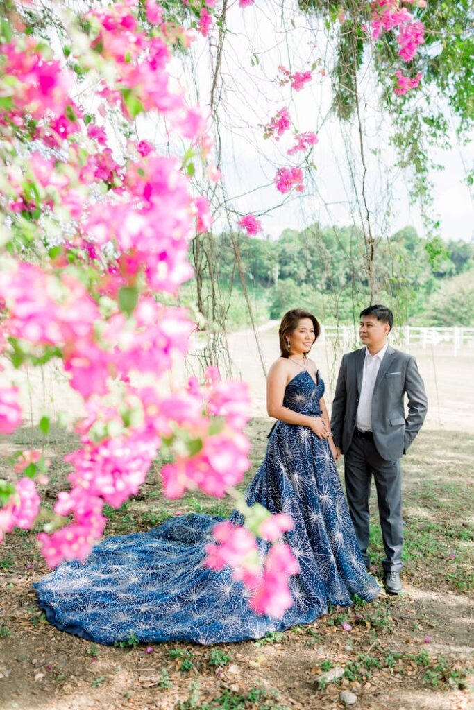 A couple poses amidst vibrant pink flowers for an outdoor engagement shoot in Davao City.